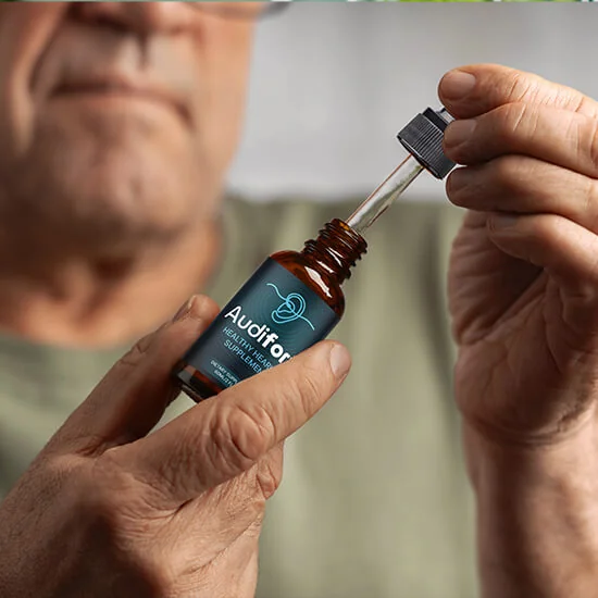 A man holding an Audifort bottle and lifting out the glass dropper